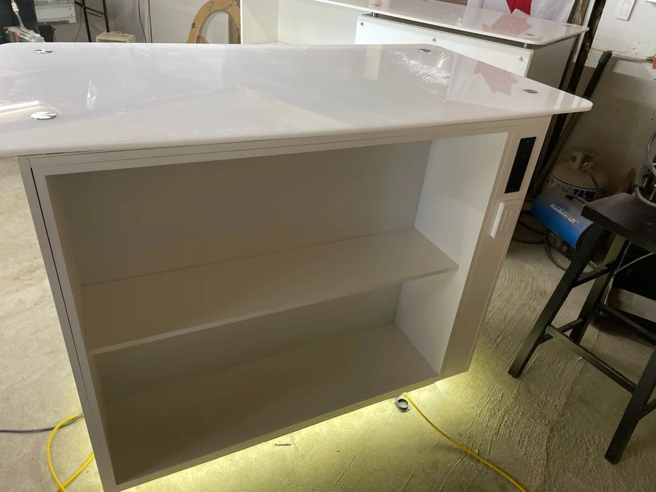 Rear of Westcoast CNC trade-show cabinet showing open storage shelves and concealed caster mobility